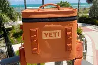 A Yeti Hopper Flip 12 Soft Cooler sits outdoors near a beach