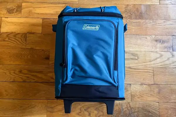 The Coleman Chiller 42-Can Soft-Sided Portable Cooler with Wheels on a wooden floor