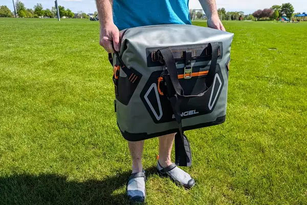 A person carries the Engel HD30 Heavy-Duty Soft-Sided Cooler Bag by the side handles