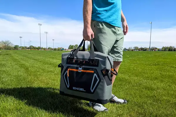 A person carries the Engel HD30 Heavy-Duty Soft-Sided Cooler Bag by the top handles