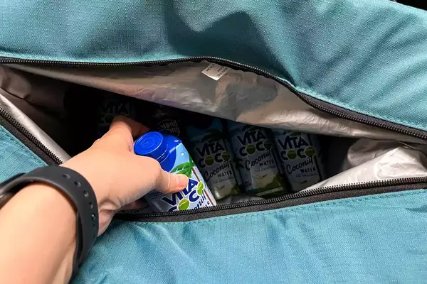 A person places a drink into the Igloo Latitude Snapdown 36-Can Cooler Bag