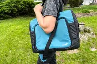 A person carries the Igloo Latitude Snapdown 36-Can Cooler Bag using the shoulder straps
