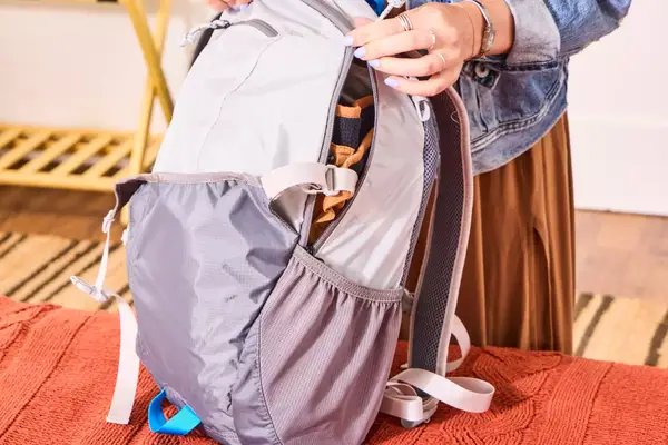 A person zips up the L.L.Bean Stowaway Day Pack