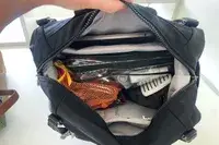 A person holds the Baggallini Nolita Convertible Backpack open to show the items inside