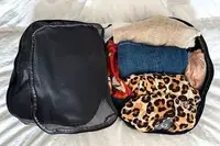 An opened filled Patagonia Black Hole Cube, Large 14L on a white surface