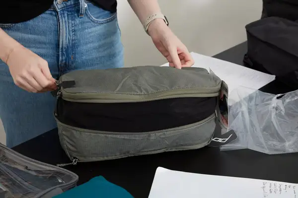 A person zippering a Patagonia Black Hole Cube, Large 14L