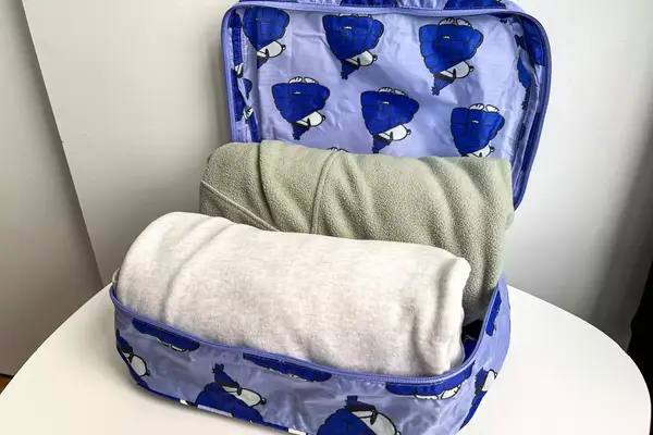 An opened part of the Baggu Packing Cube Set filled on a white table