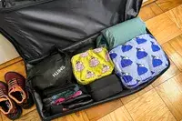 The Baggu Packing Cube Set packed in a filled suitcase