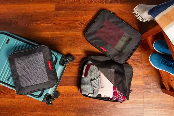 Rolled clothes in a part of the Baggu Packing Cube Set on a white table