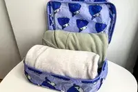 An opened part of the Baggu Packing Cube Set filled on a white table