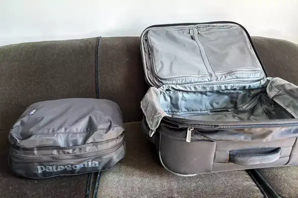 The Patagonia Black Hole Cube, Large 14L next to luggage on a couch
