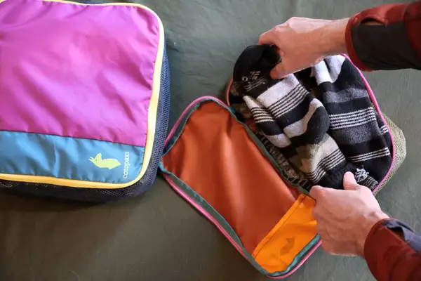 Two hands packing a Cotopaxi Cubos Packing Cubes
