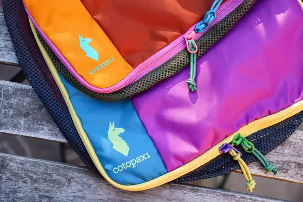 A close-up of two closed Cotopaxi Cubos Packing Cubes on a wooden surface