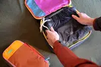 Two hands packing a Cotopaxi Cubos Packing Cube