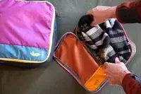 Two hands packing a Cotopaxi Cubos Packing Cubes