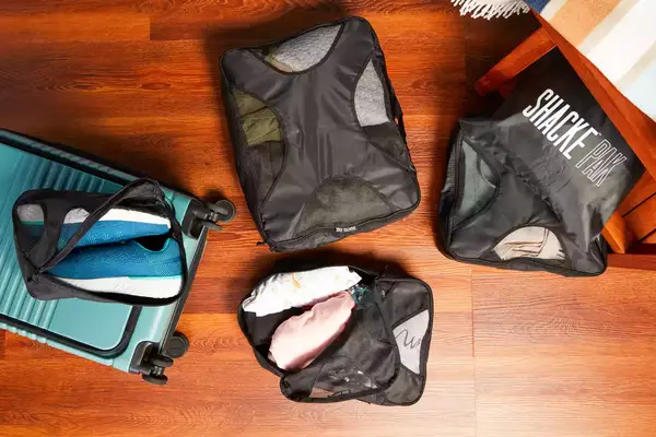 A person zippering a Patagonia Black Hole Cube, Large 14L