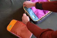 Two hands zippering closed a Cotopaxi Cubos Packing Cube
