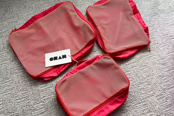 Three empty Cram Packing Cubes with tags on a rug
