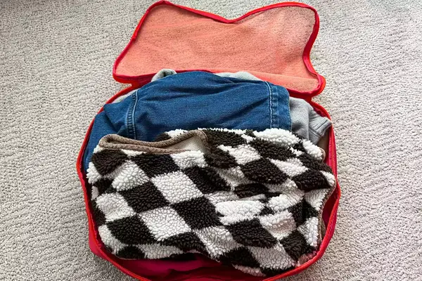 An opened filled Cram Packing Cube on a rug