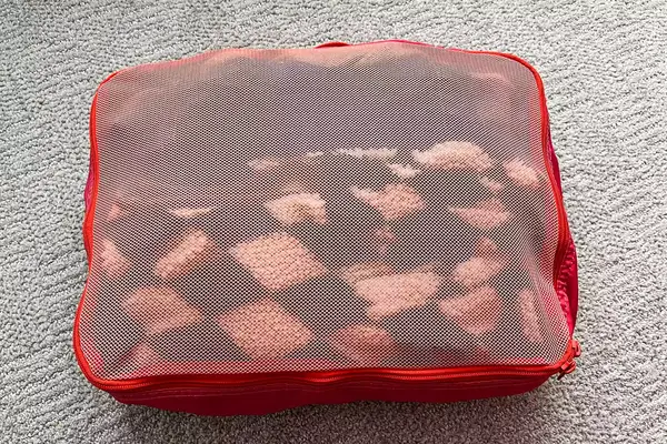 A close-up of a filled Cram Packing Cube on a rug
