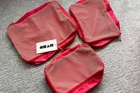 Three empty Cram Packing Cubes with tags on a rug