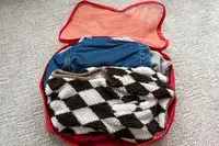 An opened filled Cram Packing Cube on a rug