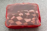 A close-up of a filled Cram Packing Cube on a rug