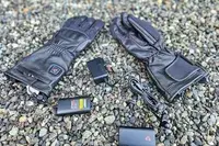 The Gerbing 7V Hard Knuckle Battery Heated Gloves with with chargers on gravel