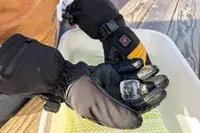 A person holds an ice cube while wearing the Gobi Heat ​​Vertex II Heated Ski Gloves
