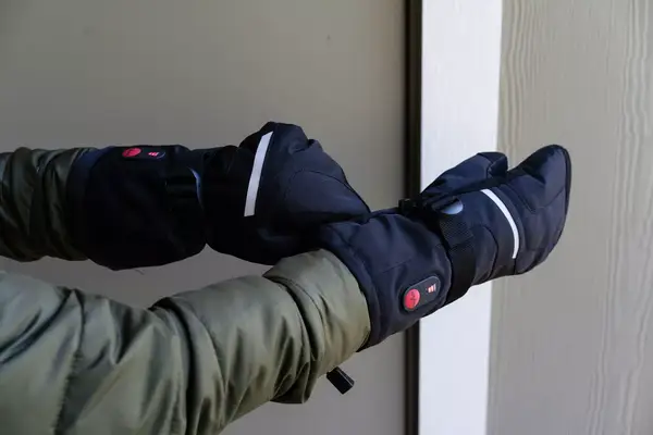 A person pulls the Snow Deer Heated Mittens on