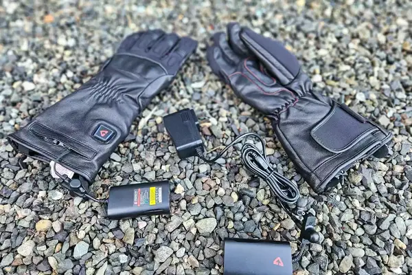 The Gerbing 7V Hard Knuckle Battery Heated Gloves with with chargers on gravel