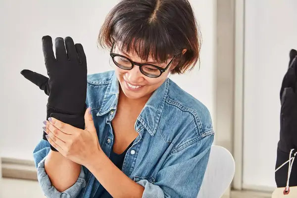 A person holds up a water bottle while wearing the Gerbing 7V Hard Knuckle Battery Heated Gloves