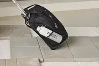 A person wheels the Rockland Melrose Upright Wheeled Underseater Luggage over paving stones