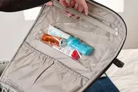 A person places travel items into the Rockland Melrose Upright Wheeled Underseater Luggage pocket
