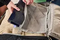 A person places a travel item into the Rockland Melrose Upright Wheeled Underseater Luggage