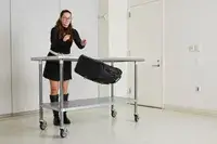 A person throws the Rockland Melrose Upright Wheeled Underseater Luggage off of a metal table