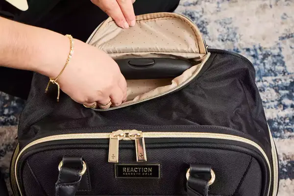 A person raises the handle on the Kenneth Cole Reaction Chelsea Luggage Expandable Underseater Spinner