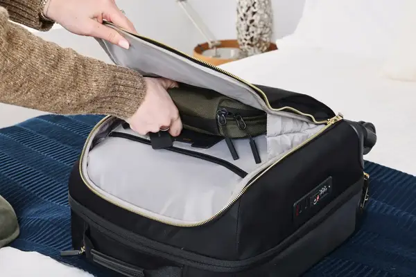 A person places a small bag into the Tumi Voyageur Léger Compact Carry-on