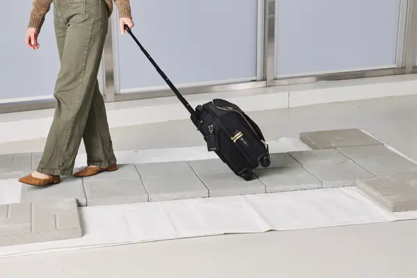 A person wheels the Tumi Voyageur Léger Compact Carry-on over paving stones
