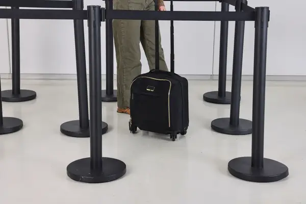 A person wheels the Tumi Voyageur Léger Compact Carry-on over a smooth floor