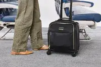 A person wheels the Tumi Voyageur Léger Compact Carry-on over carpet
