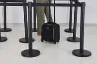 A person wheels the Tumi Voyageur Léger Compact Carry-on over a smooth floor