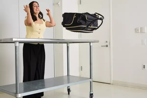 A person throws the Kenneth Cole Reaction Chelsea Luggage Expandable Underseater Spinner off of a metal table