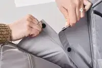 A person unsnaps buttons on the inside of the Tumi Voyageur Léger Compact Carry-on