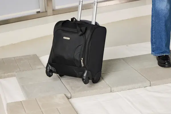 A person wheels the Samsonite Theorym Underseater over stone pavers