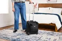 A person wheels the Samsonite Theorym Underseater over a carpet