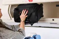 A person places the Samsonite Theorym Underseater into an overhead compartment
