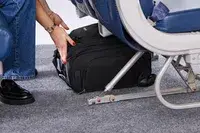 A person places the Samsonite Theorym Underseater under an airplane seat