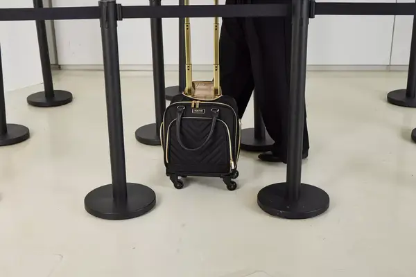 A person wheels the Kenneth Cole Reaction Chelsea Luggage Expandable Underseater Spinner across a smooth floor