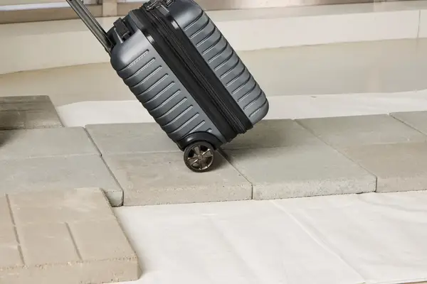 A person wheels the Delsey Paris Cruise 3.0 2-Wheeled Underseater over stone pavers